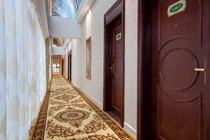 Un pasillo con alfombra decorativa, puertas de madera y un mural en el techo.