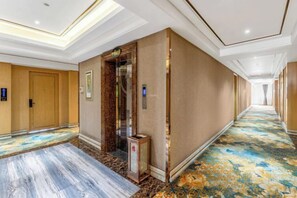 A hotel corridor with a marble floor, an elevator, and a carpeted area with a floral pattern. - Foshan Star Hotel (Huili Plaza Store) (Foshan)