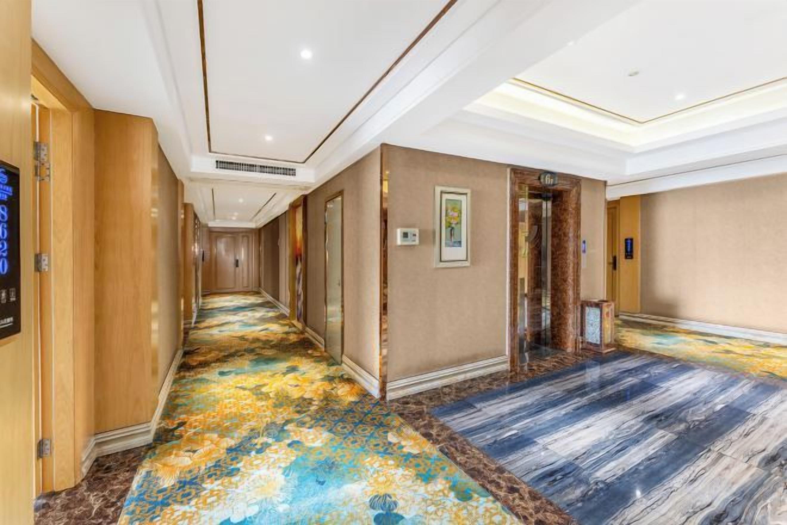 A hotel hallway with a carpeted floor, doors, and a wall-mounted sign.