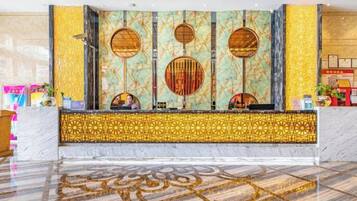 Un área de recepción con piso de mármol, una pared decorativa con diseños circulares y un mostrador de recepción.