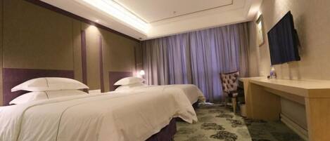A hotel room with two beds, a desk, a chair, a TV, and a patterned carpet.
