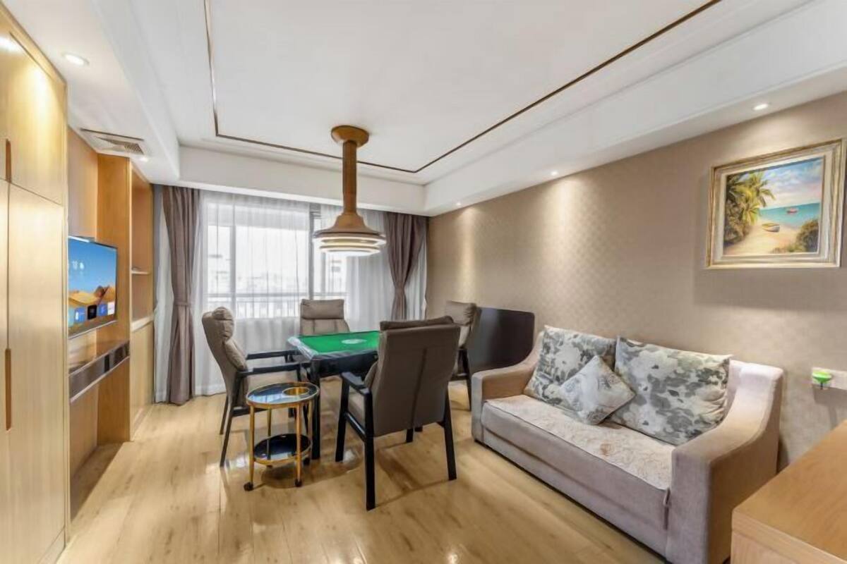 A modern living room with a pool table, sofa, and a painting of a beach scene.