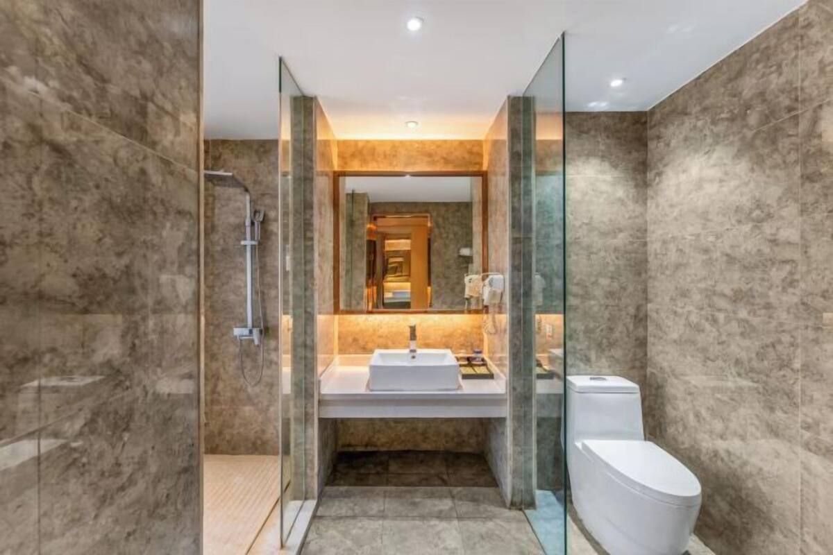 A modern bathroom with a glass-enclosed shower, a white sink, and a toilet.