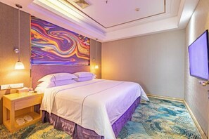 A hotel room with a large bed, a nightstand, a TV, and a colorful abstract wall mural. - Foshan Star Hotel (Huili Plaza Store) (Foshan)