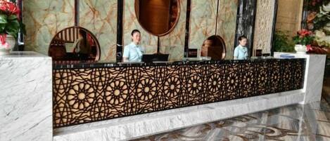 A reception desk with a marble counter, decorative panels, and a patterned floor.