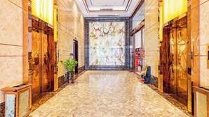 A marble-floored hallway with a large abstract mural on the far wall, flanked by wooden doors and glass panels. - Foshan Star Hotel (Huili Plaza Store) (Foshan)