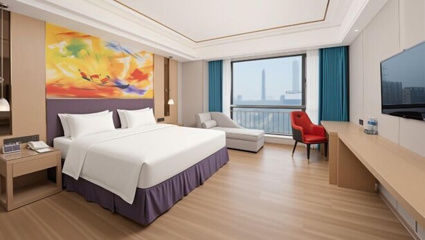 A hotel room with a bed, a desk, a chair, a TV, and a large window with a city view. - Foshan Star Hotel (Huili Plaza Store) (Foshan)