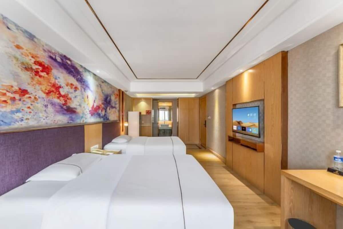A hotel room with a large bed, a television, and a reception desk.