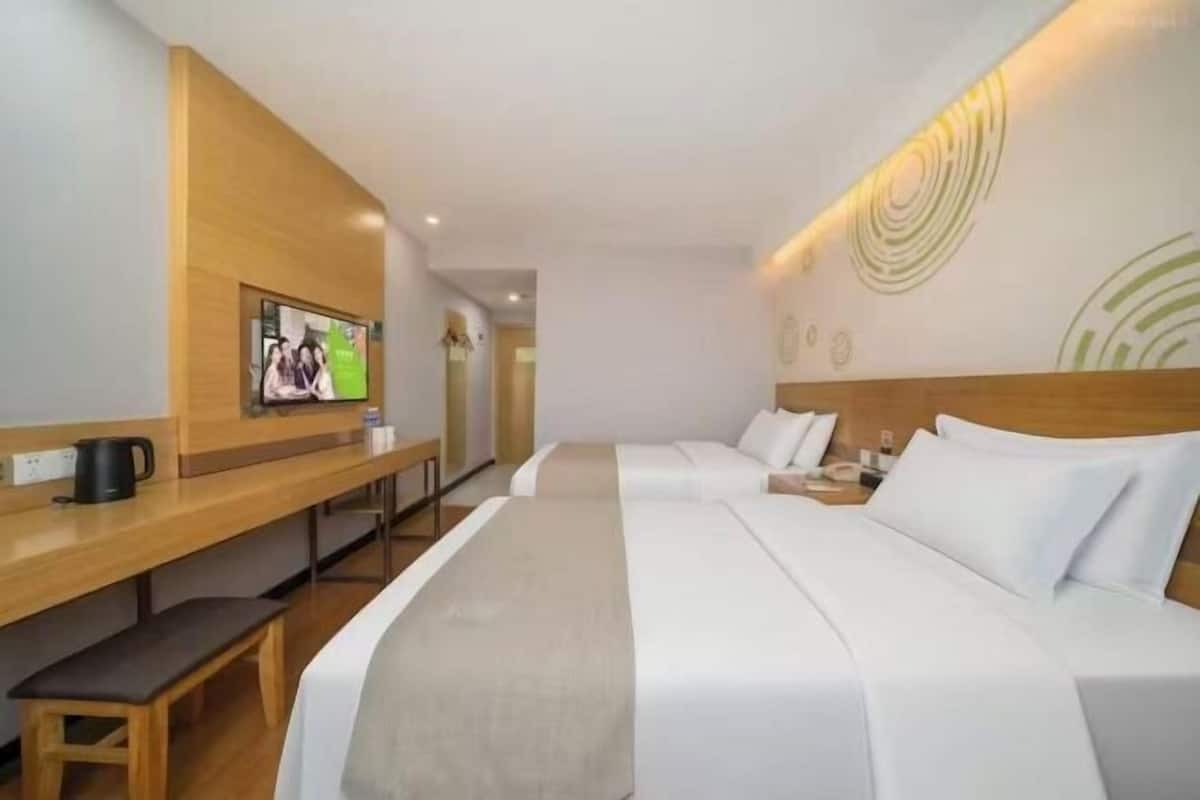A hotel room with a bed, a desk, a TV, and a bench.
