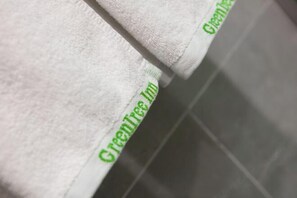 A white towel with 'GreenTree Inn' embroidered in green. - GreenTree Inn (Yancheng Hongxing Meikailong Century Avenue) (Yancheng)