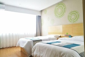 A hotel room with two beds, a wooden headboard, a window with curtains, and a wall with circular patterns. - GreenTree Inn (Yancheng Hongxing Meikailong Century Avenue) (Yancheng)