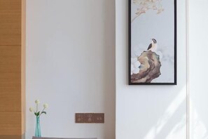 A framed artwork of a bird on a rock, a vase with flowers, and a wall socket. - GreenTree Inn (Yancheng Hongxing Meikailong Century Avenue) (Yancheng)