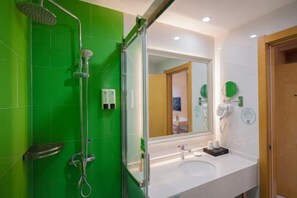 A bathroom with green tiles, a shower, a sink with toiletries, and a mirror. - GreenTree Inn (Yancheng Hongxing Meikailong Century Avenue) (Yancheng)