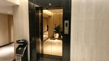 An elevator with a modern design, a trash bin, and a potted plant.