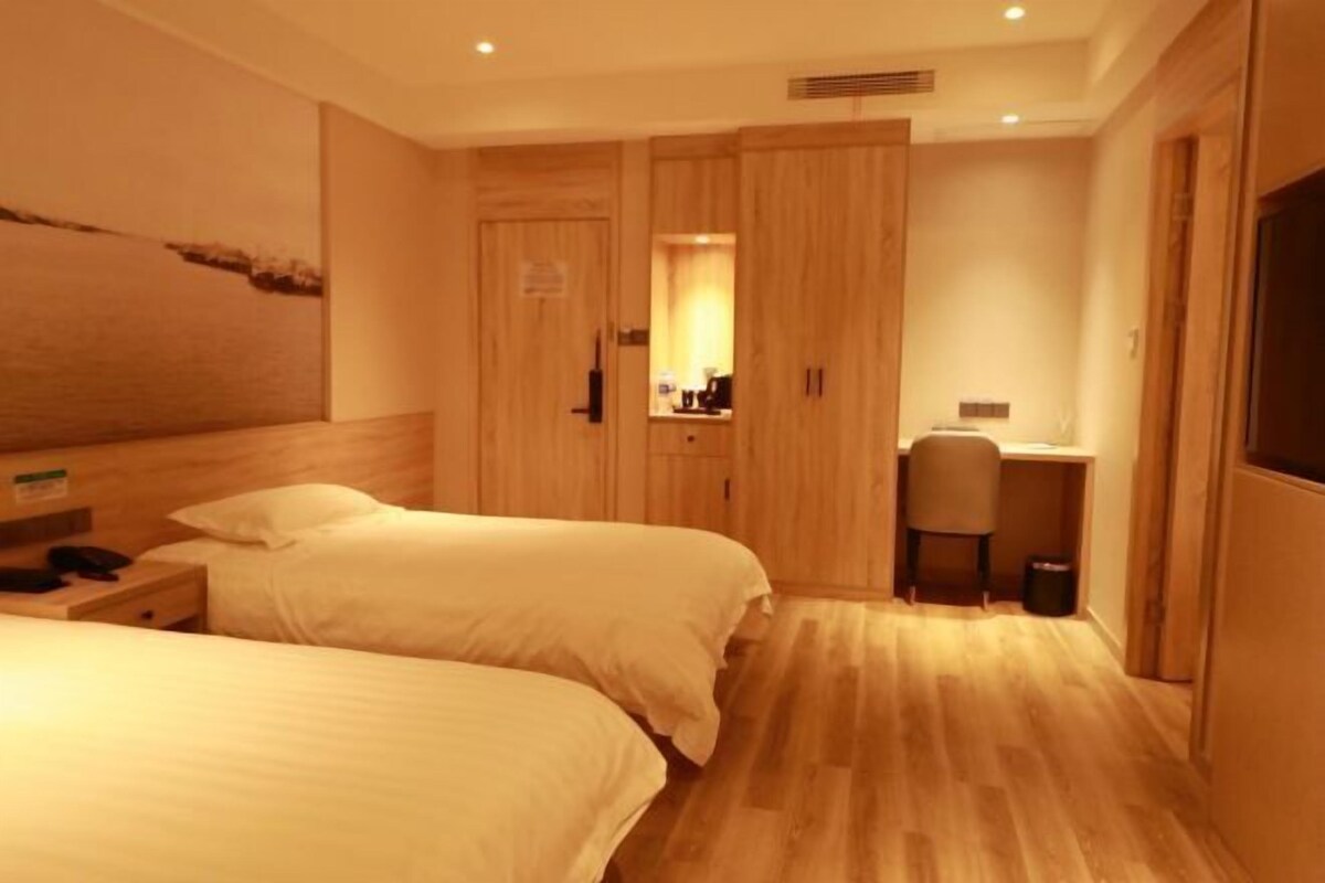 A hotel room with two beds, a desk, and a chair.