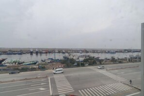 A view of a harbor with boats docked, a road with vehicles, and a pedestrian crossing. - Rudong Victoria Hotel (Rudong)