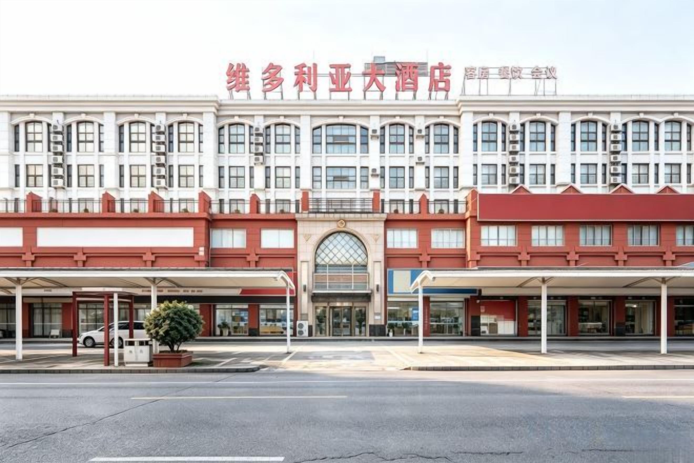A hotel with a red and white facade, multiple windows, and a covered entrance area.