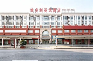 Un hotel con fachada roja y blanca, numerosas ventanas y un área de acceso cubierta.