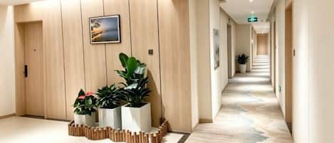 Un pasillo de hotel con pared de madera, un cuadro enmarcado y plantas en macetas.