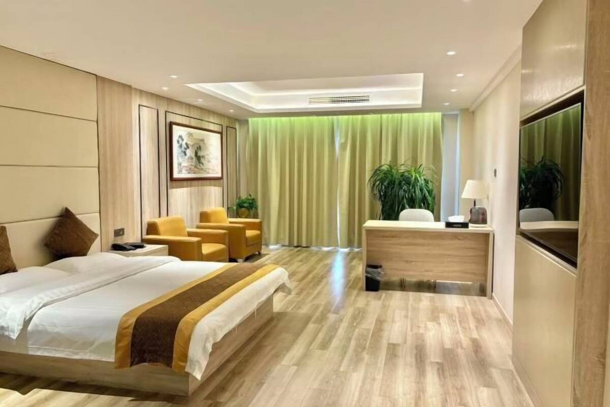 A modern hotel room with a large bed, a desk, and a seating area with chairs.