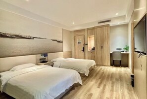 A hotel room with two beds, a desk, a chair, a wardrobe, and a large artwork on the wall.
