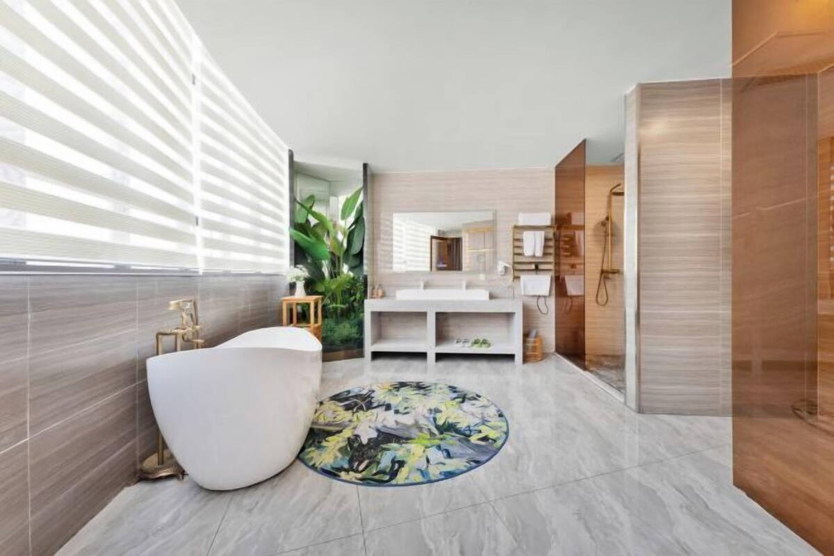 A modern bathroom with a white bathtub, a round rug, and a large mirror.