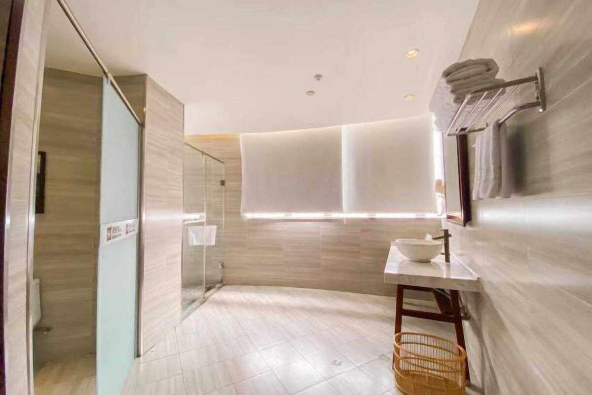A modern bathroom with a glass shower enclosure, a sink with a mirror, and a towel rack.