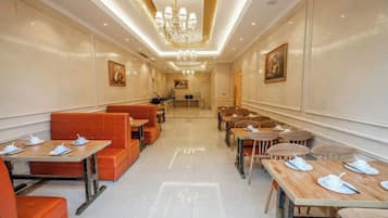 A hotel dining area with tables and booths, a chandelier, and artwork on the walls.