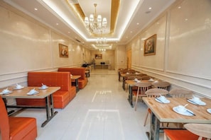 Un comedor de hotel con mesas y cabinas, una araña y obras de arte en las paredes.