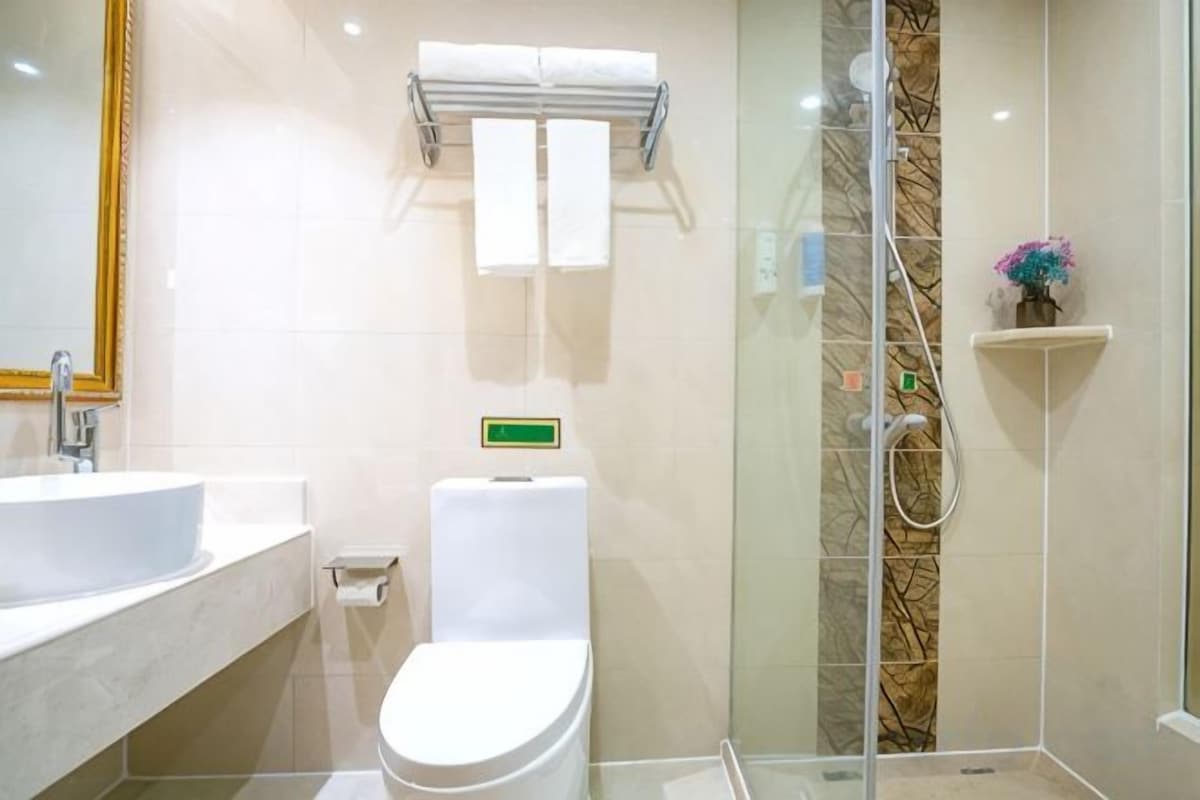 A modern bathroom with a glass-enclosed shower, a white toilet, and a sink.