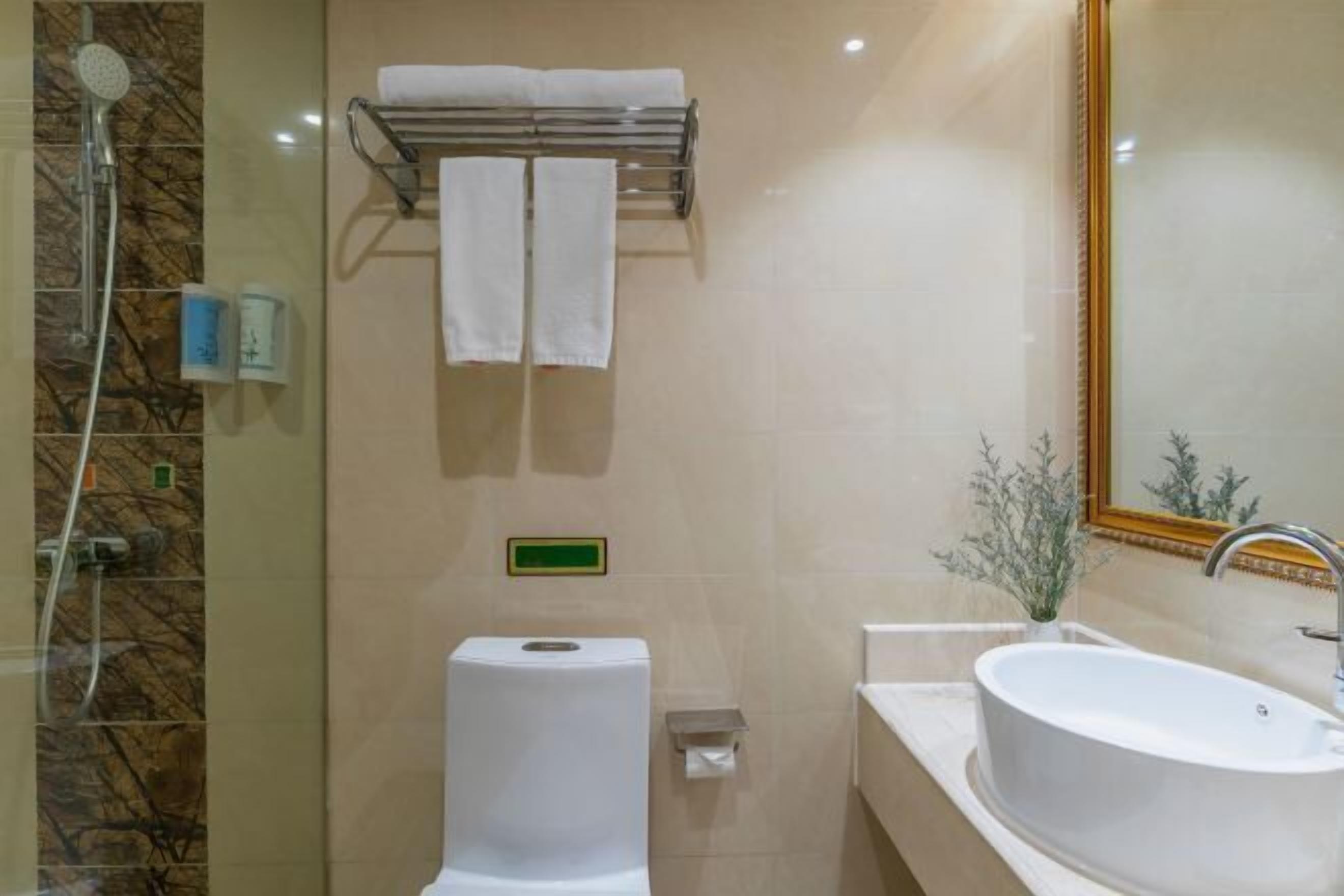 A modern bathroom with a shower, toilet, sink, and towel rack.