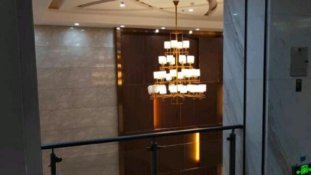 A modern interior with a large, ornate chandelier, marble walls, and a metal railing. - Xunwu Hotel (Xunwu)