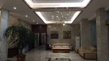 A modern lobby with a reception desk, seating area, and a large potted plant.