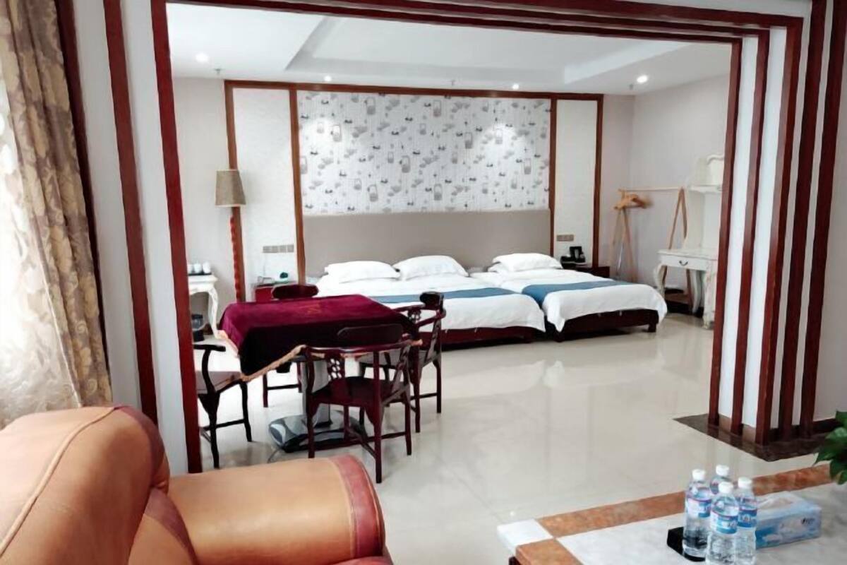 Habitación de hotel con cama, escritorio, silla y mesa con botellas de agua.