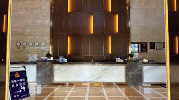 A hotel reception area with a marble counter, a digital display, and a signboard.