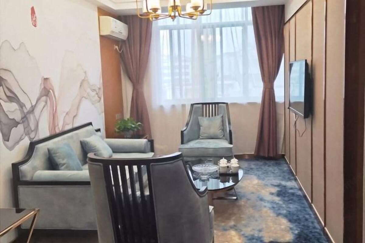 Una sala de estar moderna con un sofá, dos sillones, una mesita de centro y un televisor montado en la pared.