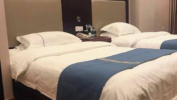 A hotel room with two beds, each with white bedding and a blue accent.