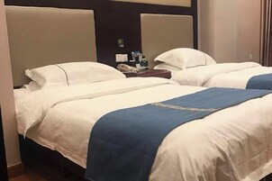 Habitación de hotel con dos camas, cada una con ropa blanca y detalles azules.