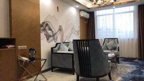 A hotel room with a modern design, featuring a sofa, a chair, a small table, and a decorative wall piece. - Xunwu Hotel (Xunwu)