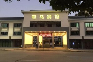 A building with a sign that reads 'Finding a Bird.' It has a large entrance with a canopy and a sign above it. - Xunwu Hotel (Xunwu)