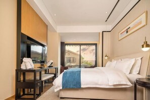 A hotel room with a bed, a desk, a chair, a TV, and a window with a view. - U-house Villa Hotel (Anning)