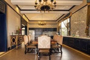 A formal dining room with a chandelier, dark wood furniture, and marble walls. - U-house Villa Hotel (Anning)