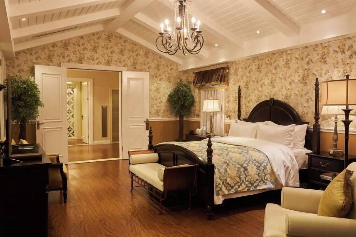 Un dormitorio con una cama con dosel, un candelabro, una mesita de noche y una silla.