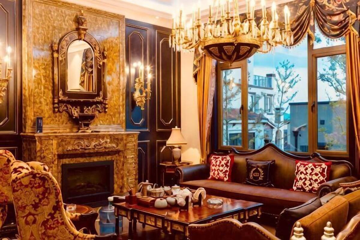 Una habitación lujosa con chimenea, muebles ornamentales y un amplio ventanal con vistas.