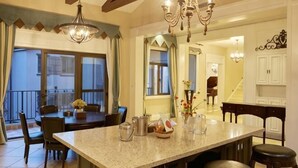 Uma cozinha ampla com uma ilha grande, banquetas e um lustre.