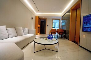 A modern living room with a sofa, a glass coffee table, and a TV mounted on the wall. - U-house Villa Hotel (Anning)