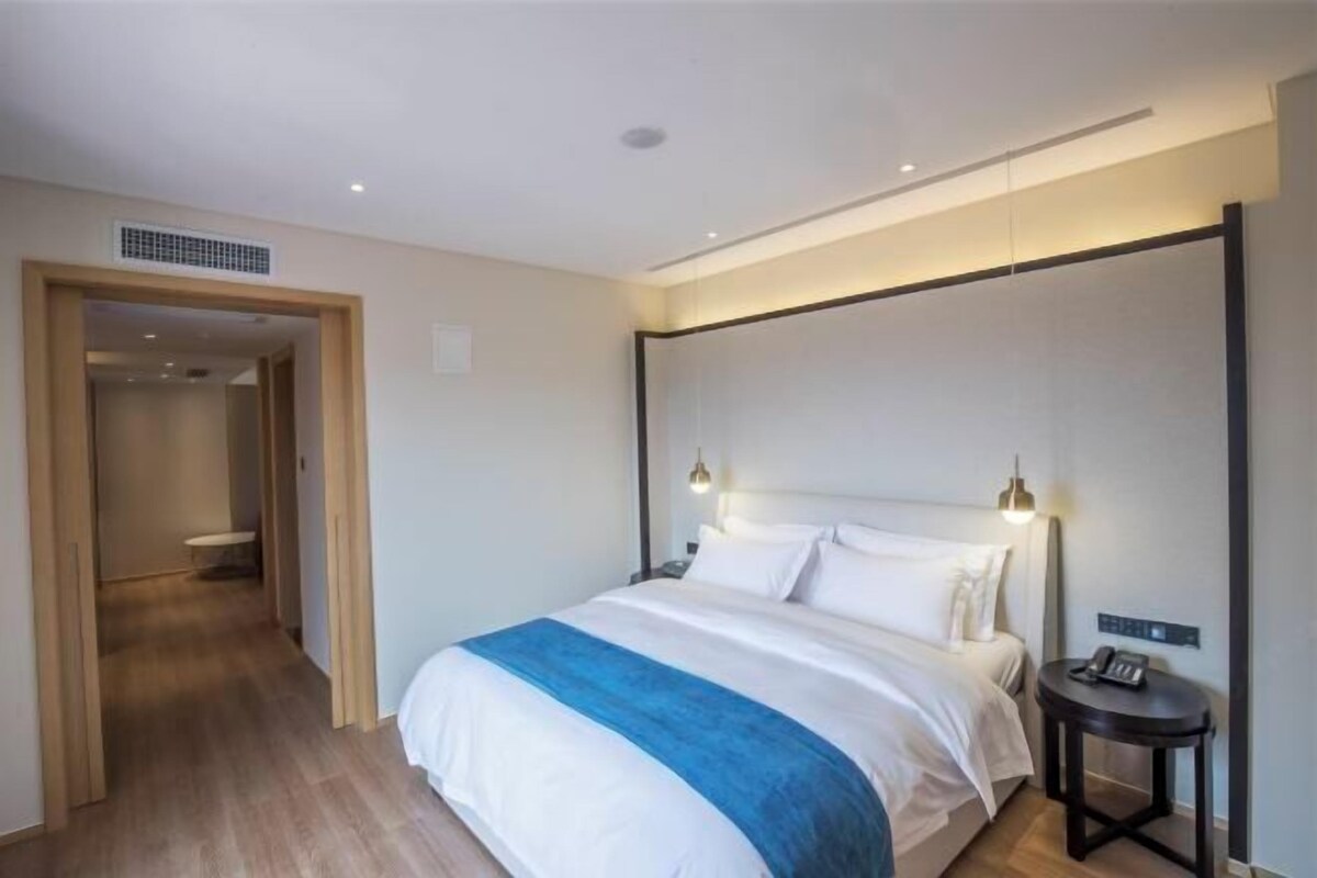 A hotel room with a bed, bedside table, and a lamp.