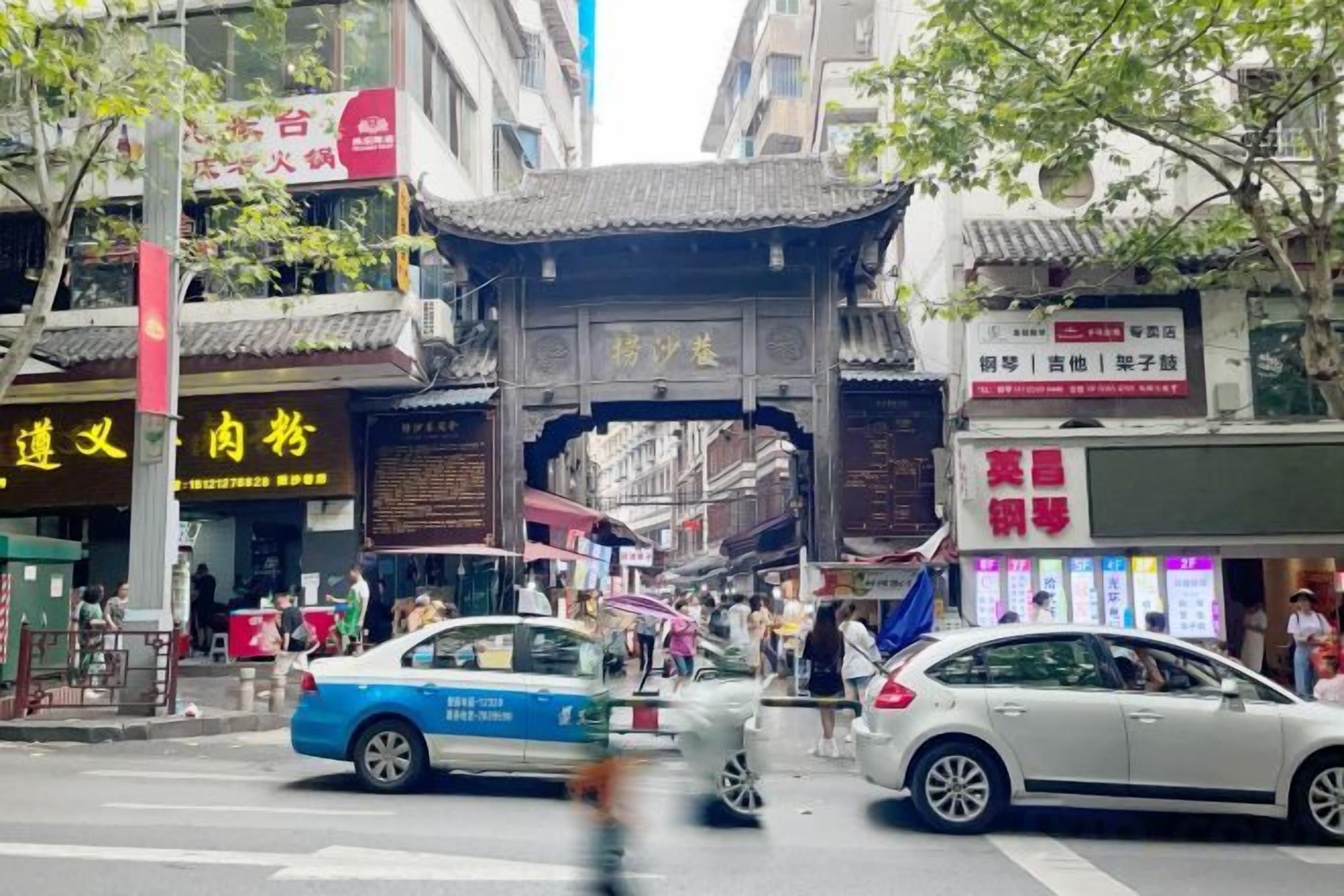 Una calle concurrida con arquitectura tradicional, que incluye una puerta y señalización en un idioma extranjero.
