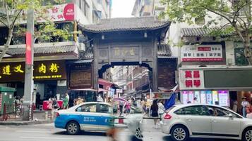 Una calle concurrida con arquitectura tradicional, que incluye una puerta y señalización en un idioma extranjero.