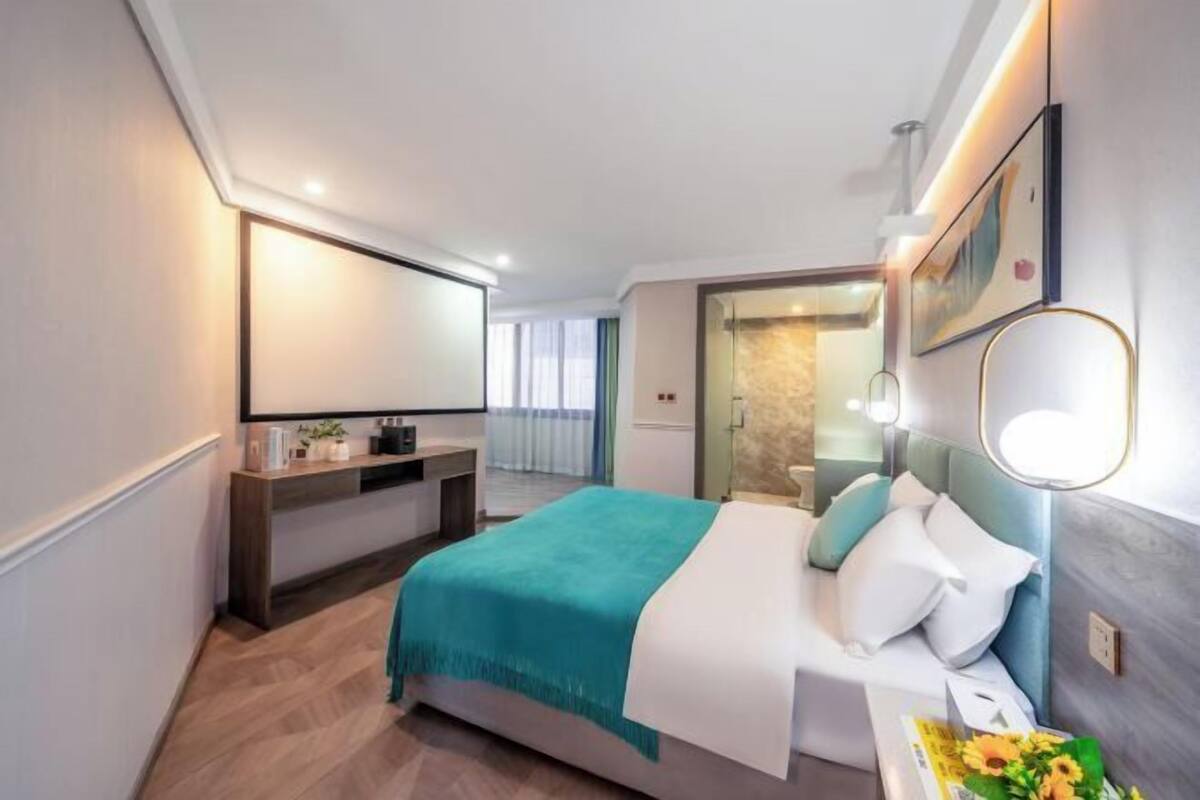 A modern hotel room with a bed, bedside table, and a mirror.